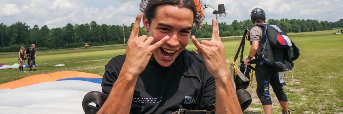 tandem student flashes rock on hand sign after skydive
