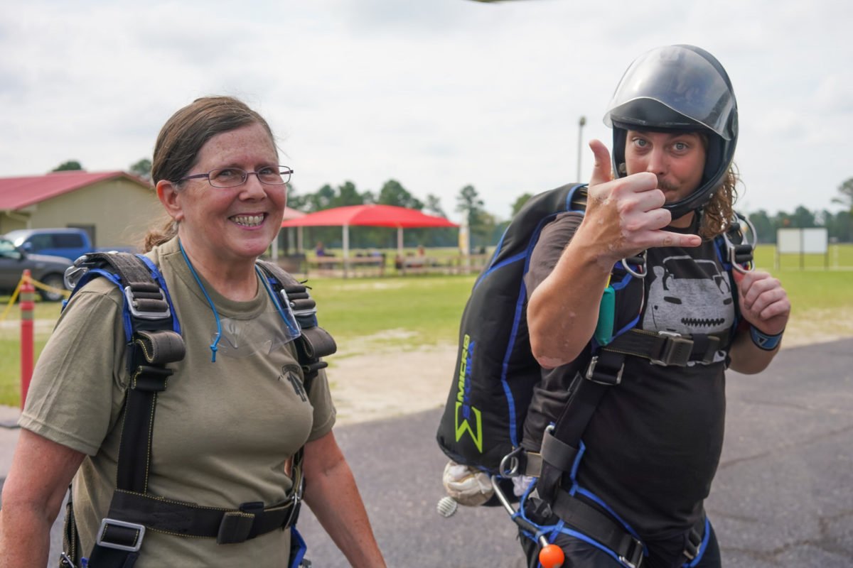 Tandem student and instructor walk toward plane to go skydiving 