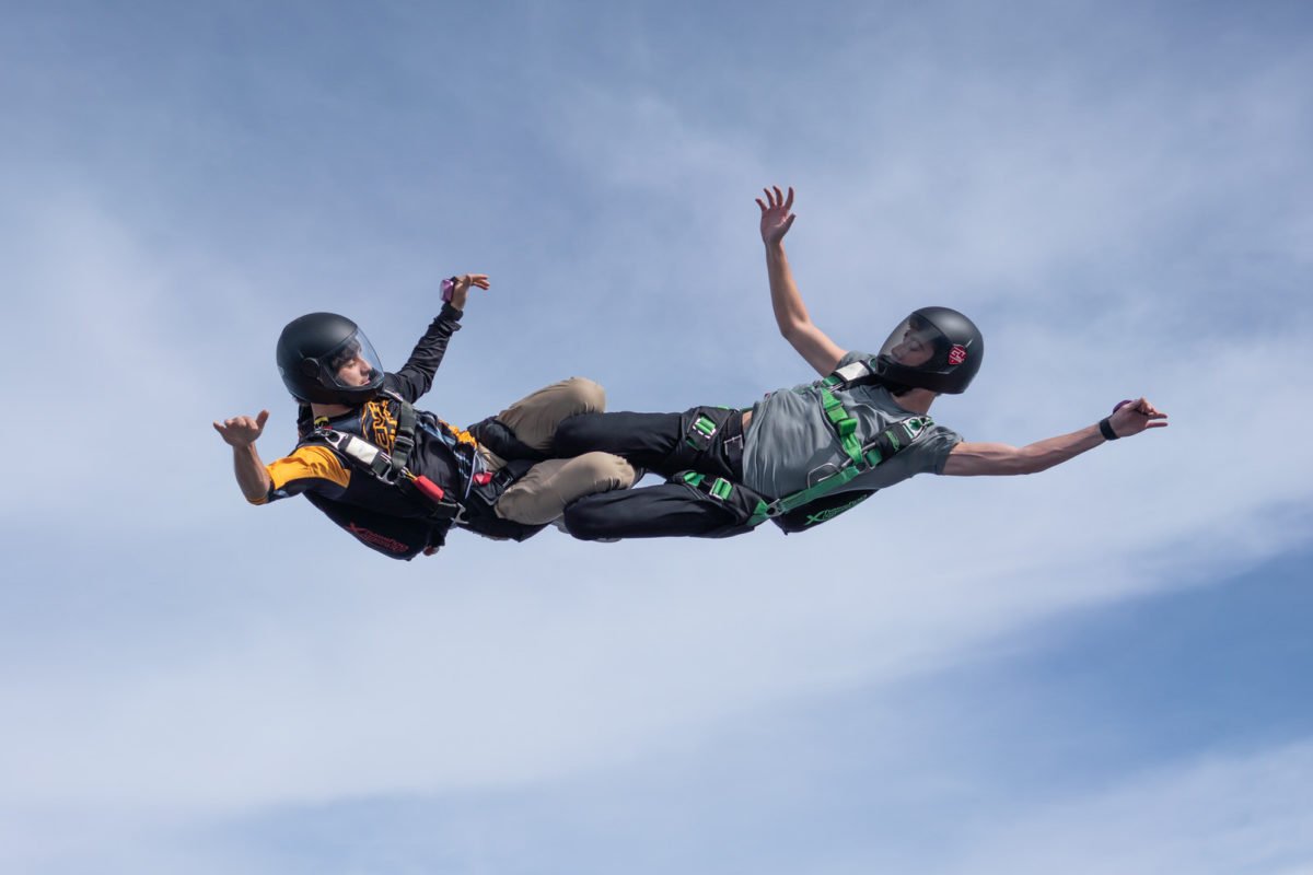 Two skydivers in freefall interlock their legs 
