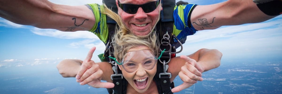 tandem skydivers in freefall smile at the camera