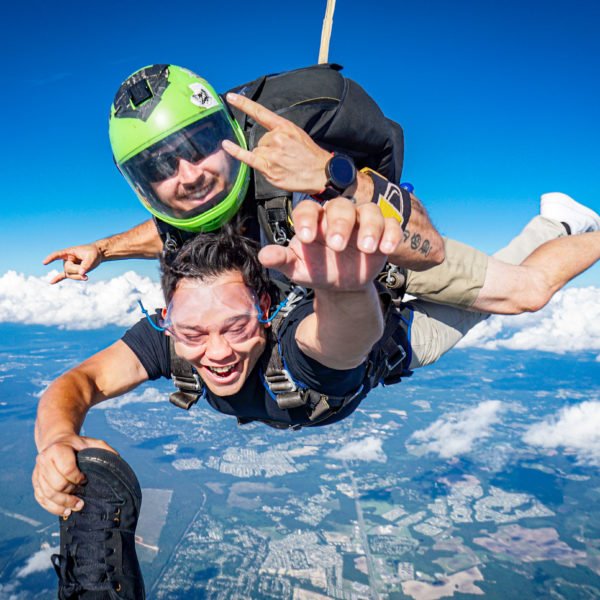 tandem skydiver grabs videographer foot in freefall