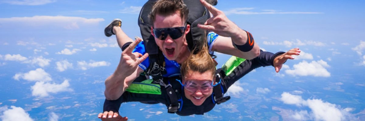 tandem skydivers give rock on symbol and smile in freefall