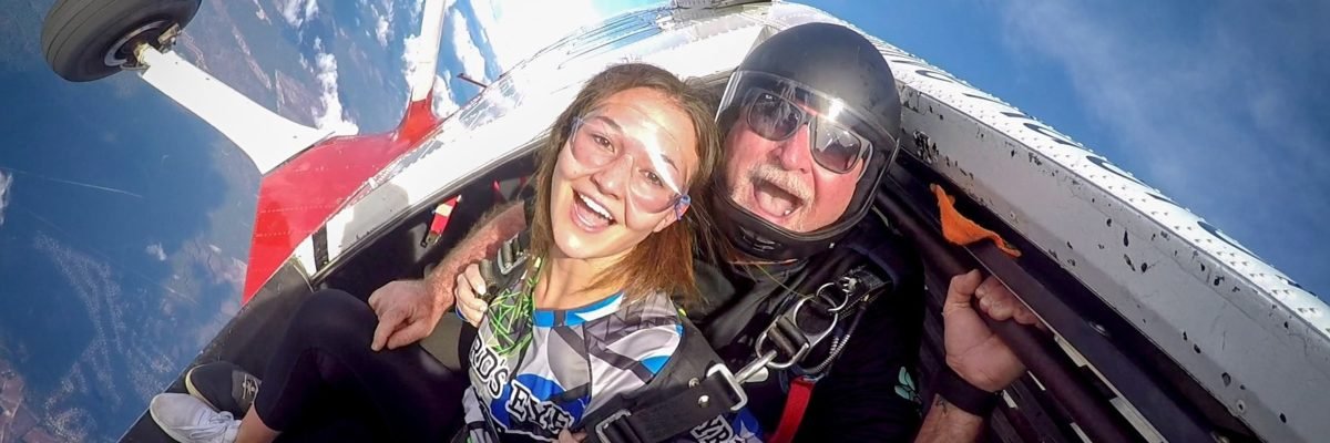 tandem skydivers grin at camera prior to exiting the airplane