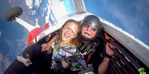 tandem skydivers grin at camera prior to exiting the airplane