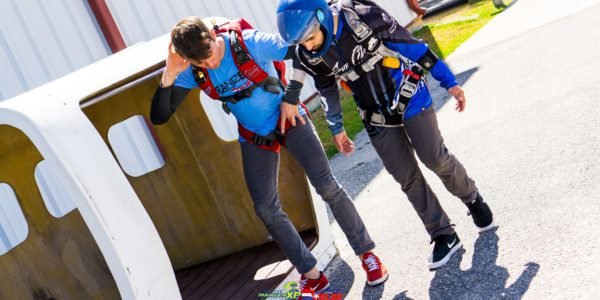 two experienced skydivers mock up their skydive exit on the ground before they skydive