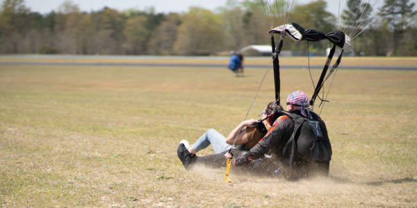 Tandem skydiving pair slide in on their backsides for a nice landing.