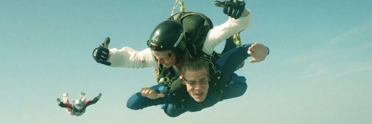 Tandem student and instructor pair with another licensed skydiver behind.
