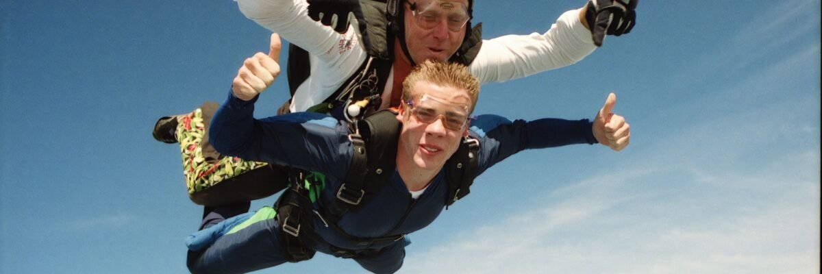Male tandem student and instructor give a thumbs up during freefall.