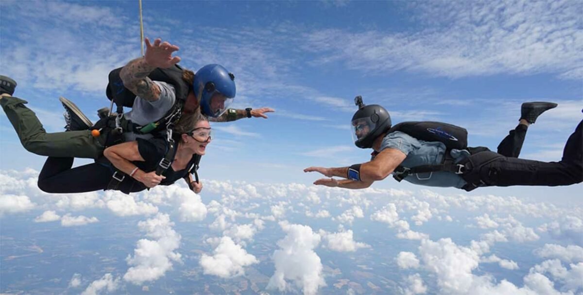 Outside photo of a videographer in mid air filming a tandem student in freefall with her instructor